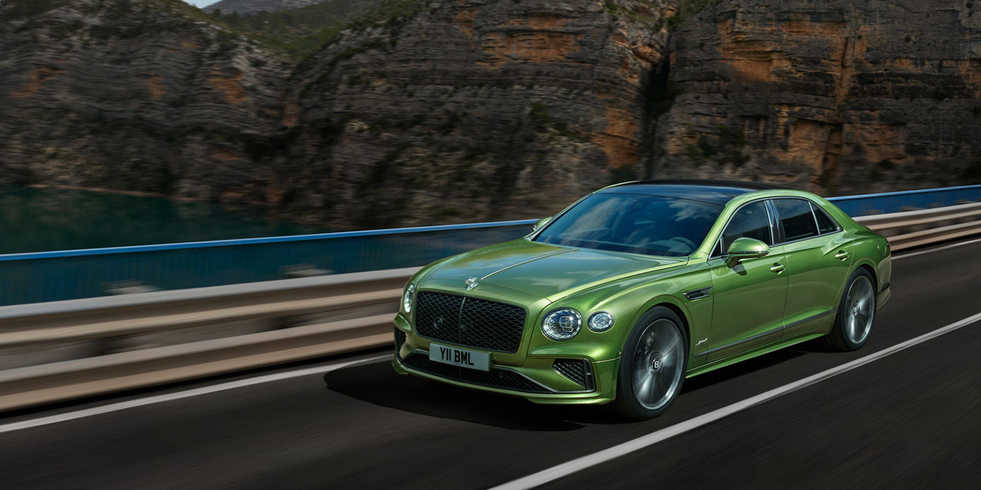 Bentley Madrid Bentley New Flying Spur Speed v8 hybrid sedan driving dynamically on a mountain road in Tourmaline Green paint