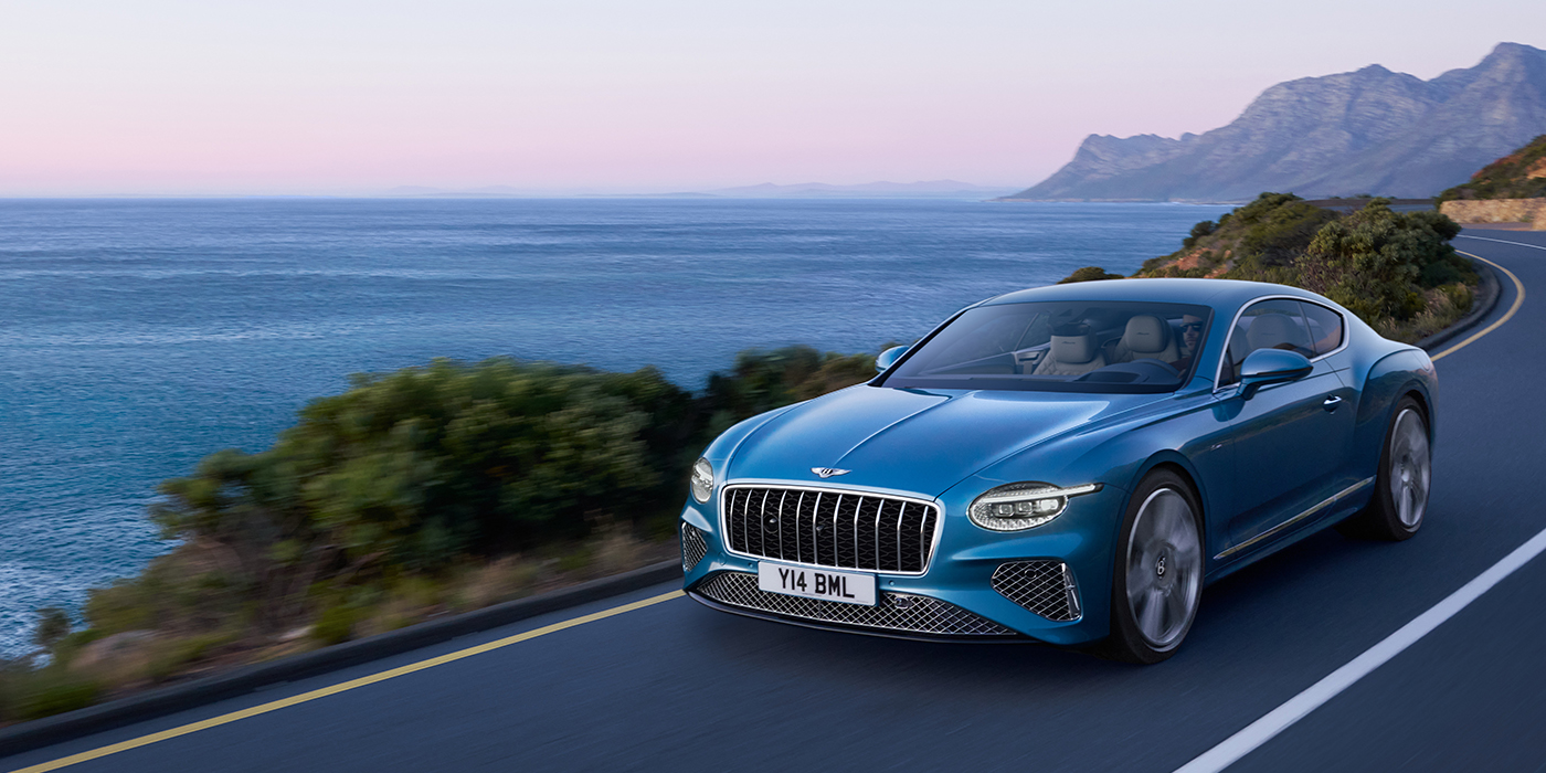 Bentley Madrid New Bentley Continental GT Azure coupe in Light Windsor blue paint with 22 inch Azure wheels and chrome grill, driving dynamically by the sea