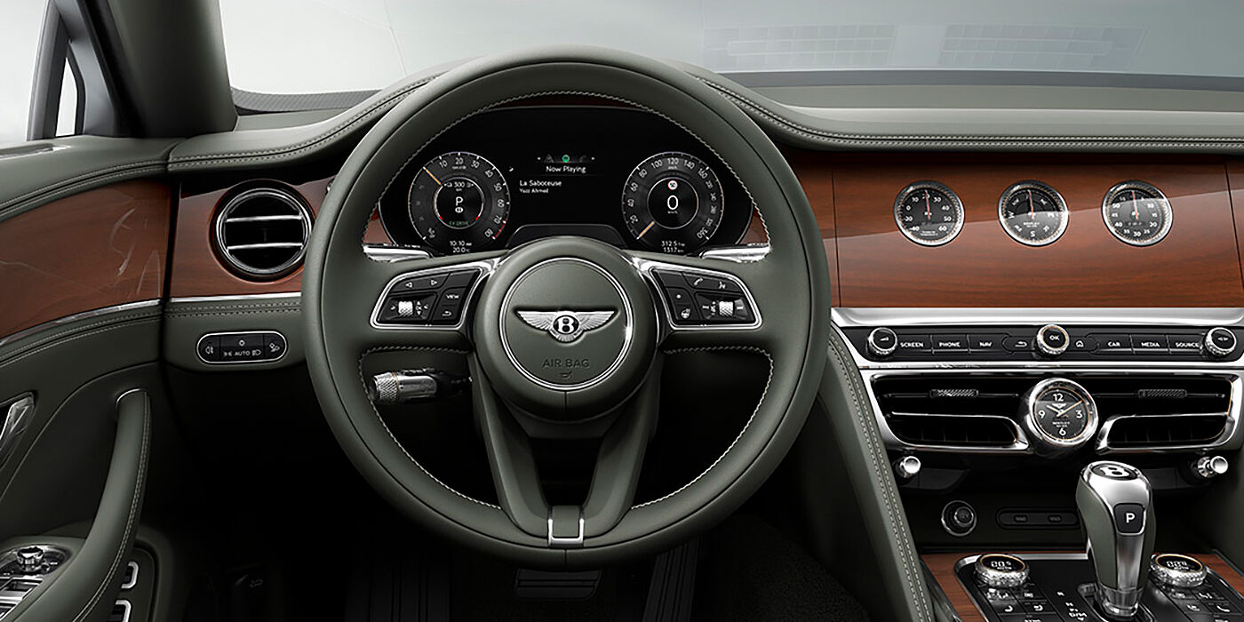 Bentley Madrid New Bentley Flying Spur sedan front cabin in Cumbrian Green hide and Crown Cut walnut veneer showing steering wheel and Rotating Display with three clocks on face