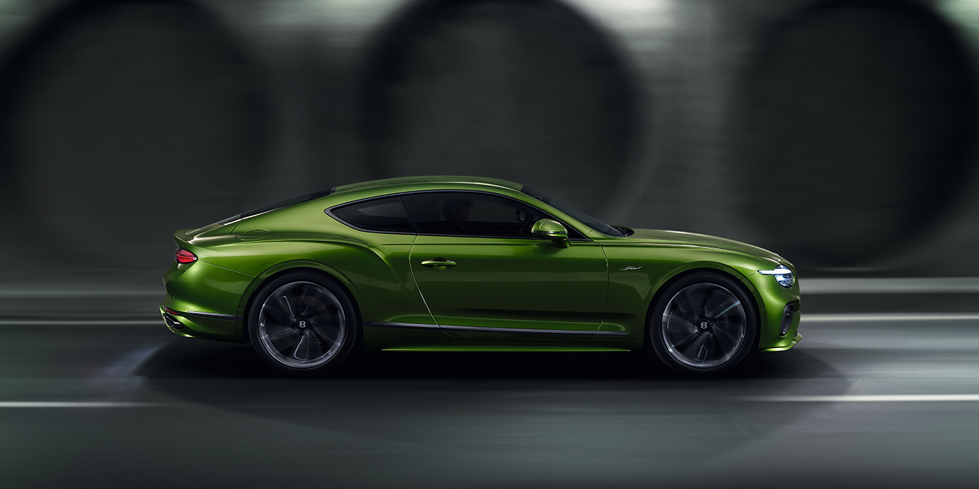 Bentley Madrid Bentley Continental GT coupe in Tourmaline Green paint driving in profile on a dark road